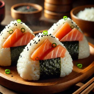 A close-up of freshly made smoked salmon onigiri, triangular rice balls filled with flaked smoked salmon, wrapped in a strip of nori, and sprinkled with toasted sesame seeds and chopped green onions. Served on a wooden plate with a small bowl of soy sauce and a cup of green tea in a cozy Japanese-inspired kitchen setting.