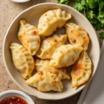 Crispy pan-fried chicken dumplings with dipping sauce.